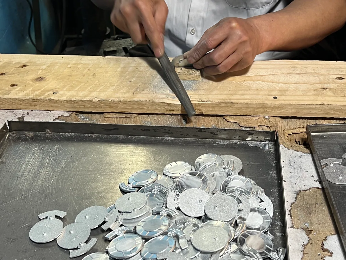 Worker manually removing burrs from cast custom pin bodies