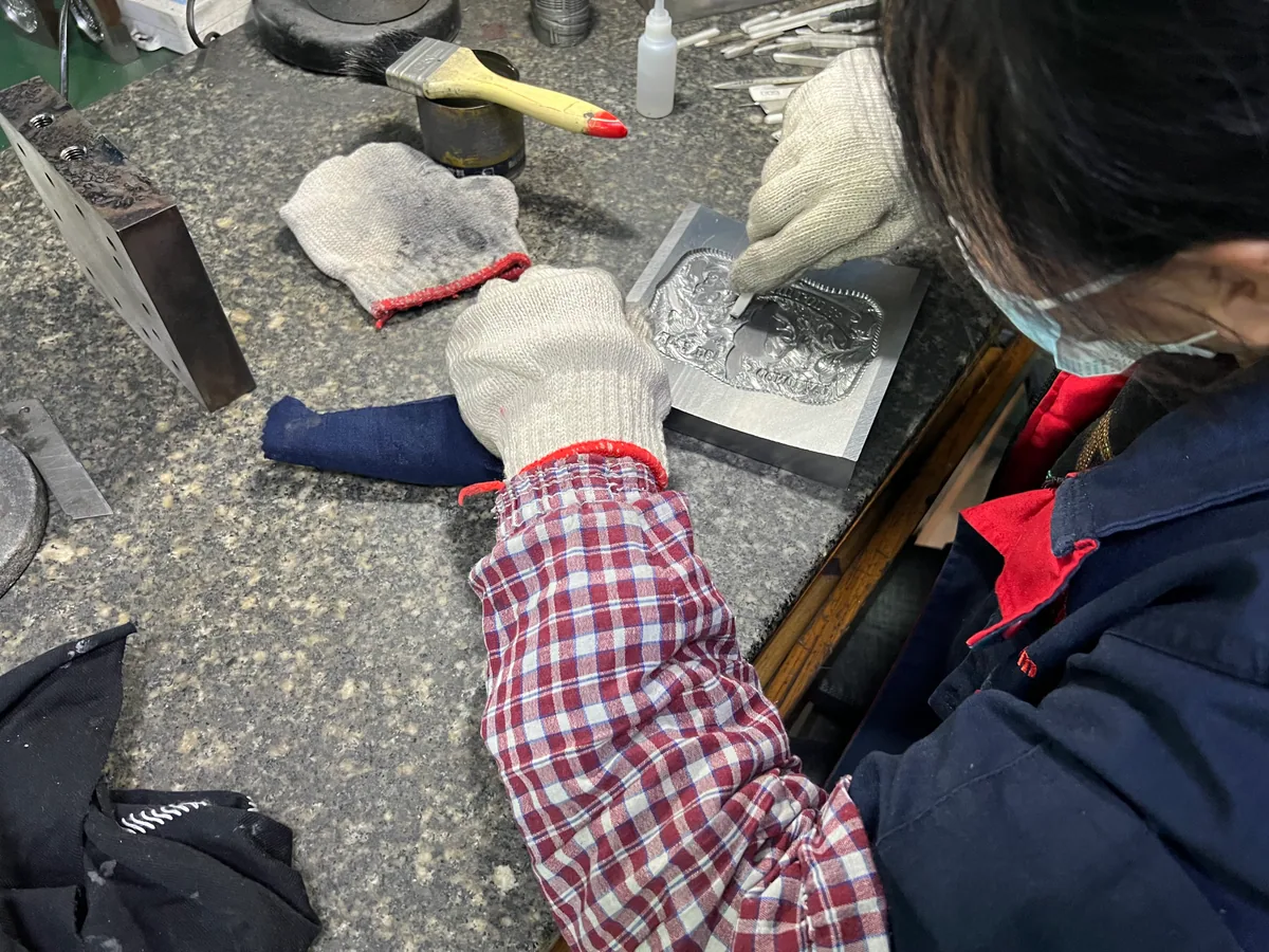 Worker hand-finishing a metal mold for custom pin production