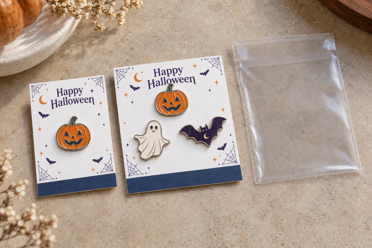 A pumpkin pin on an individual backing card beside a three-pin Halloween set